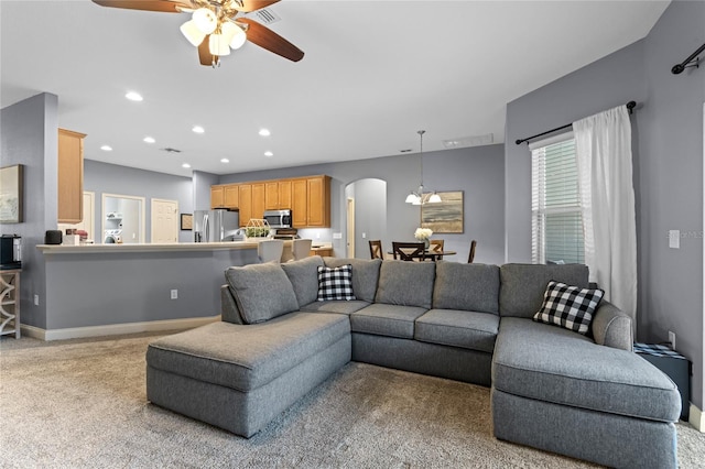 carpeted living room with ceiling fan with notable chandelier