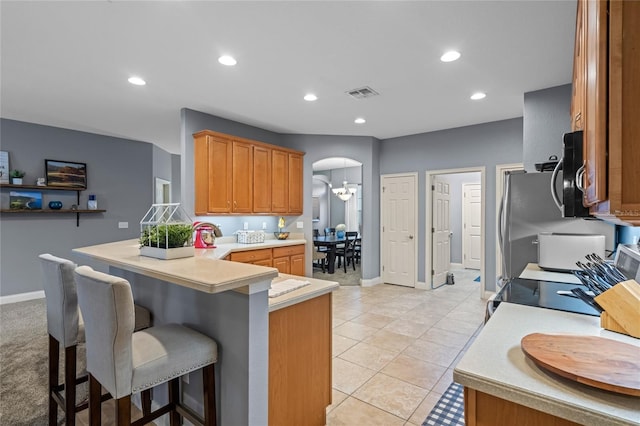 kitchen featuring a breakfast bar, kitchen peninsula, and light tile patterned floors