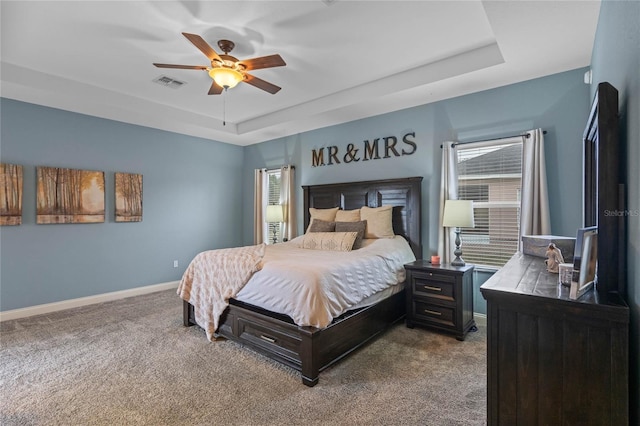 bedroom with ceiling fan, carpet floors, and a tray ceiling