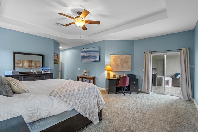 carpeted bedroom featuring ceiling fan and a tray ceiling