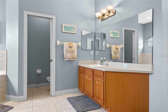 bathroom featuring toilet, a tub, tile patterned floors, and vanity