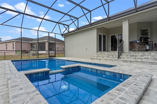 view of pool with glass enclosure, an in ground hot tub, and a patio area