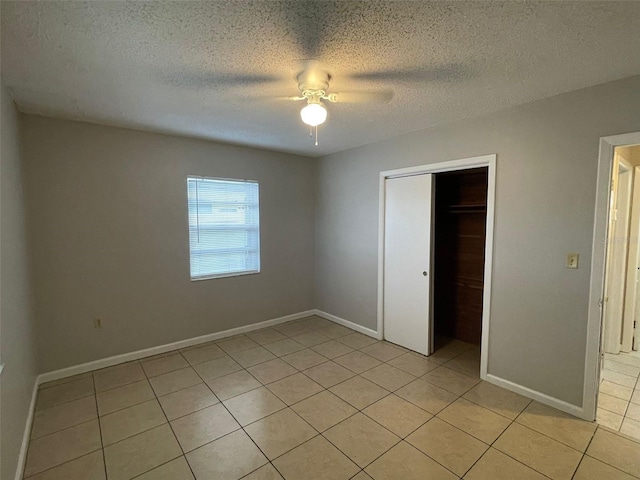 unfurnished bedroom featuring light tile patterned floors, a textured ceiling, a closet, and ceiling fan