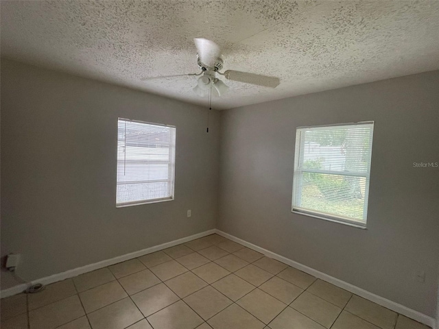 unfurnished room with a wealth of natural light, light tile patterned floors, and a textured ceiling