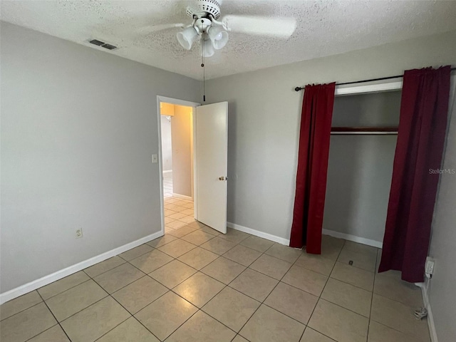 unfurnished bedroom with ceiling fan, a closet, light tile patterned floors, and a textured ceiling