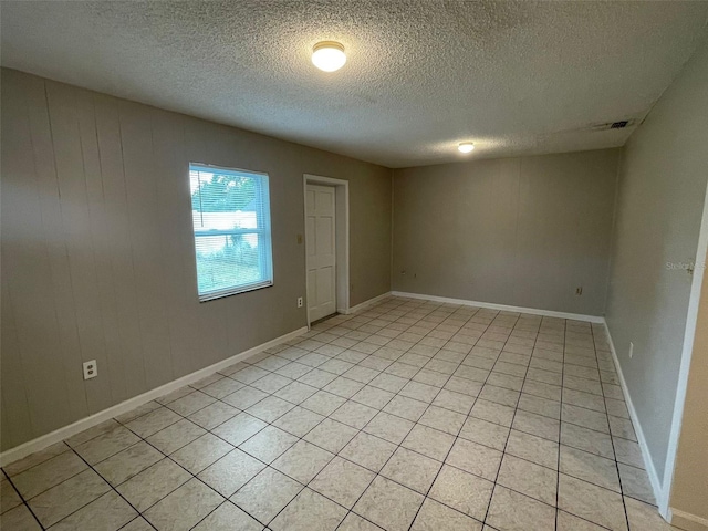 empty room featuring a textured ceiling and wood walls