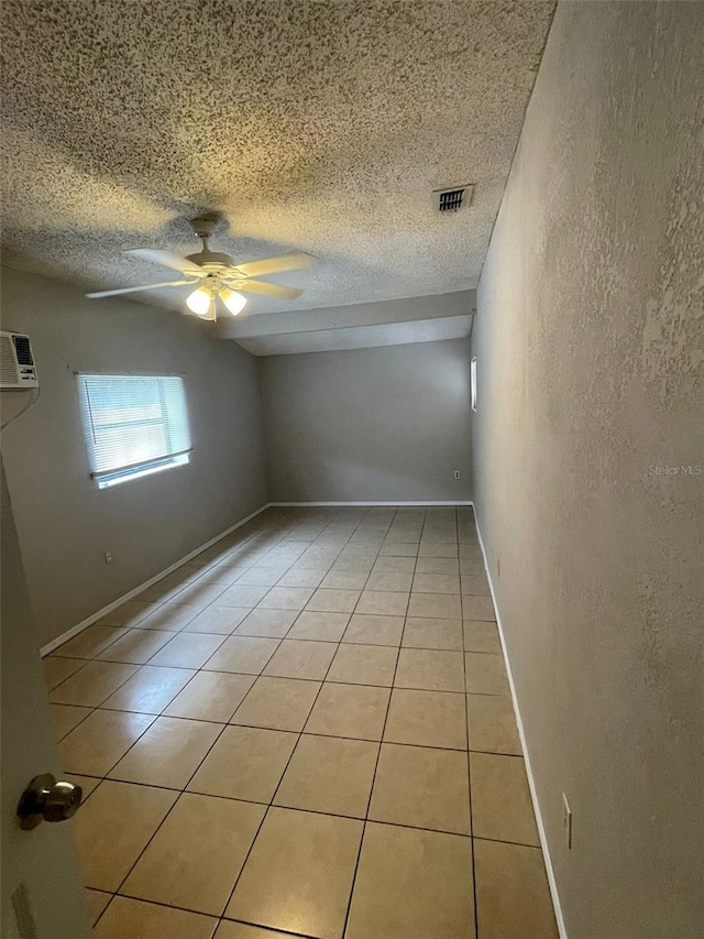 spare room featuring a wall mounted air conditioner, ceiling fan, and light tile patterned flooring