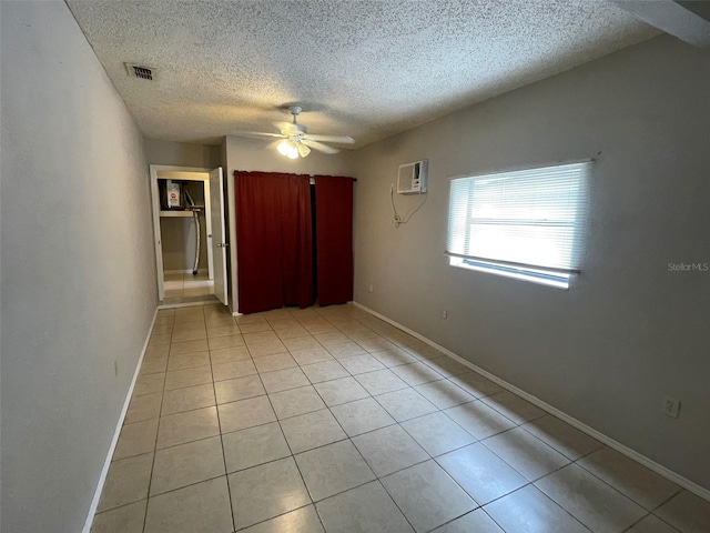 interior space with a wall mounted AC, a textured ceiling, ceiling fan, and light tile patterned flooring