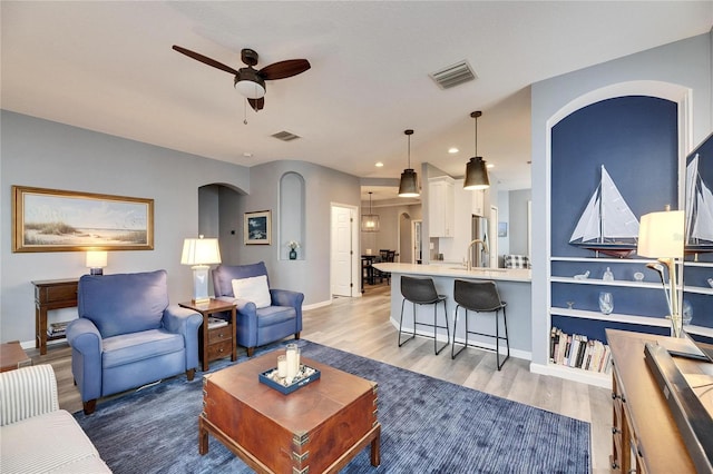 living room featuring ceiling fan, sink, and hardwood / wood-style floors