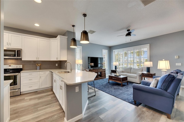 kitchen with sink, white cabinets, kitchen peninsula, and stainless steel appliances