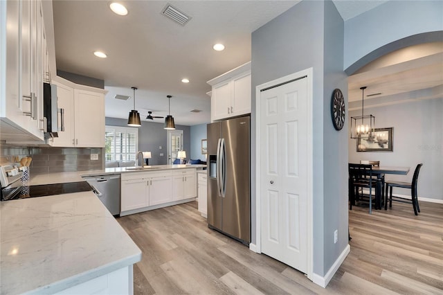 kitchen with tasteful backsplash, white cabinets, stainless steel appliances, and pendant lighting