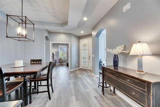 dining space featuring light wood-type flooring, french doors, and an inviting chandelier