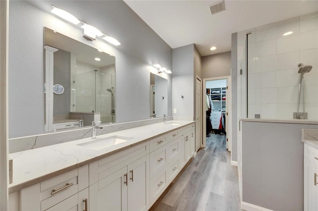 bathroom with a shower with shower door, hardwood / wood-style flooring, and vanity