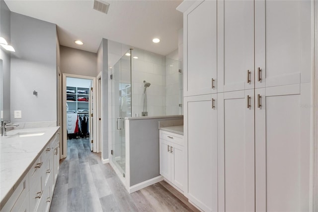 bathroom with wood-type flooring, a shower with door, and vanity