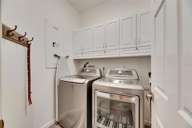 clothes washing area featuring cabinets and washer and clothes dryer