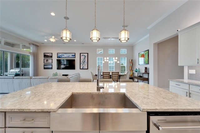 kitchen featuring a center island with sink, pendant lighting, crown molding, white cabinets, and sink