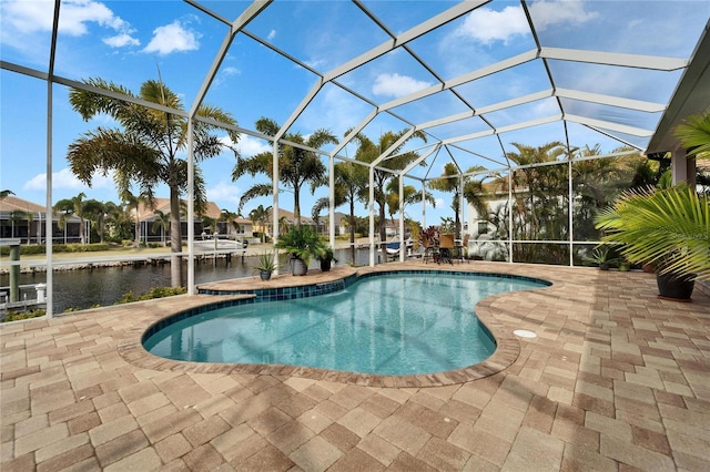 view of swimming pool featuring glass enclosure, a water view, and a patio