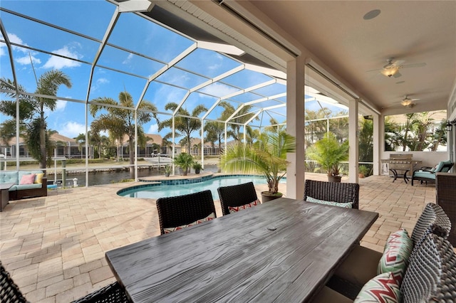 view of patio featuring a lanai, ceiling fan, an outdoor living space, area for grilling, and a water view