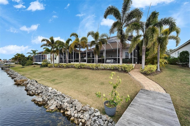 back of house featuring a lanai, a water view, and a lawn