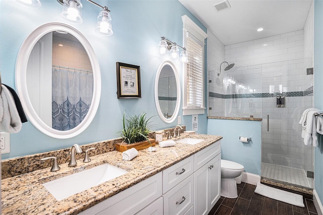 bathroom with vanity, a shower with shower door, and toilet