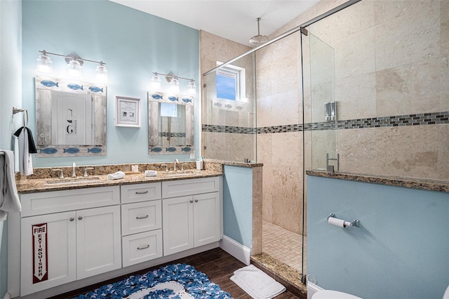 bathroom featuring a tile shower, vanity, and wood-type flooring