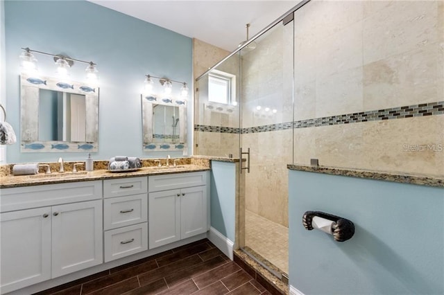 206 Church Ave, Bradenton Beach, FL 34217 - bathroom featuring a stall shower, wood tiled floor, double vanity, and a sink