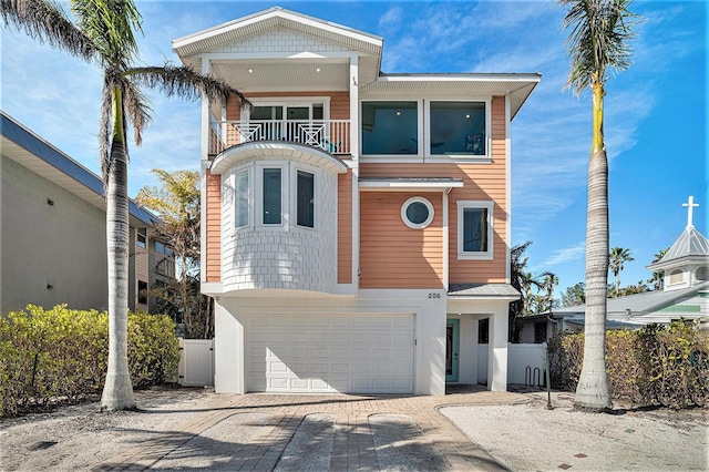 206 Church Ave, Bradenton Beach, FL 34217 - view of front of house with stucco siding, fence, a balcony, driveway, and a garage