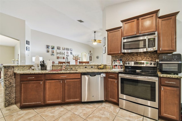 kitchen featuring light stone countertops, appliances with stainless steel finishes, vaulted ceiling, and sink