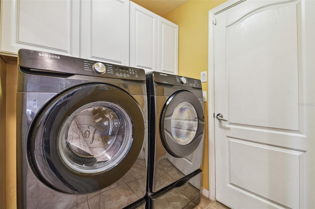 clothes washing area featuring cabinets, washing machine and clothes dryer, and light tile patterned floors