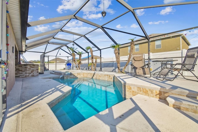 view of swimming pool featuring a patio area, glass enclosure, and an in ground hot tub