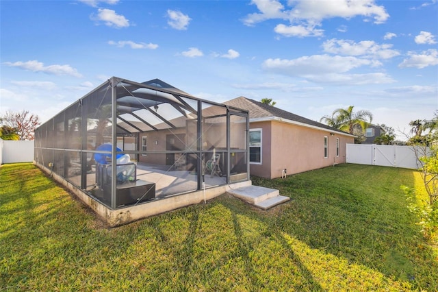 rear view of house with a lawn, glass enclosure, and a patio area