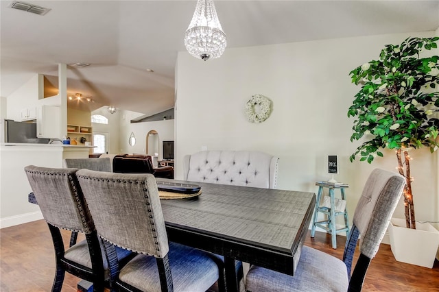 dining area featuring lofted ceiling, dark hardwood / wood-style floors, and an inviting chandelier