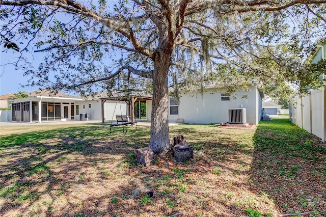 rear view of property featuring central AC, a sunroom, and a lawn