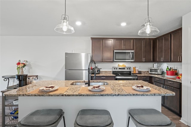 kitchen featuring appliances with stainless steel finishes, a center island with sink, hanging light fixtures, and sink