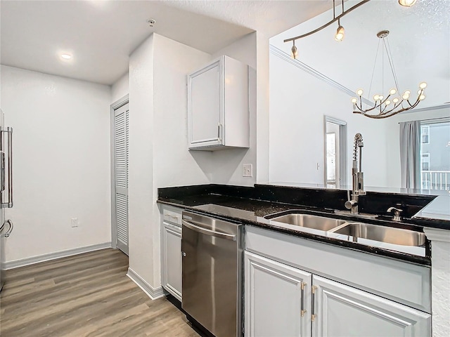 kitchen featuring dark stone counters, pendant lighting, sink, an inviting chandelier, and stainless steel dishwasher