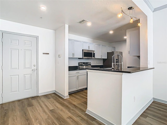 kitchen featuring stainless steel appliances, dark hardwood / wood-style flooring, decorative light fixtures, and kitchen peninsula