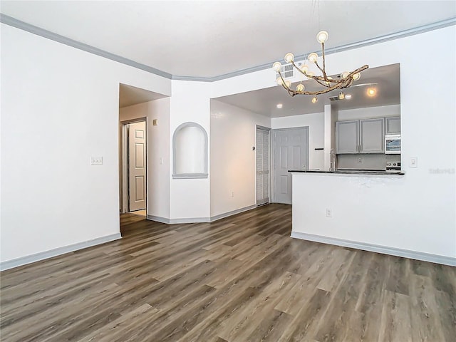 unfurnished living room with a chandelier, crown molding, and dark hardwood / wood-style floors