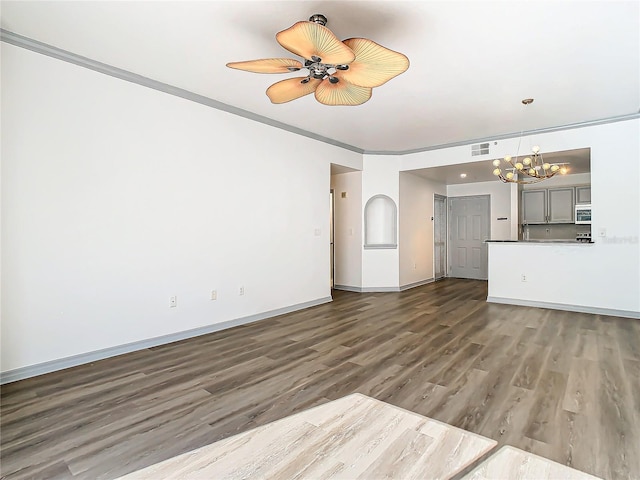 unfurnished living room featuring an inviting chandelier, crown molding, and dark hardwood / wood-style floors