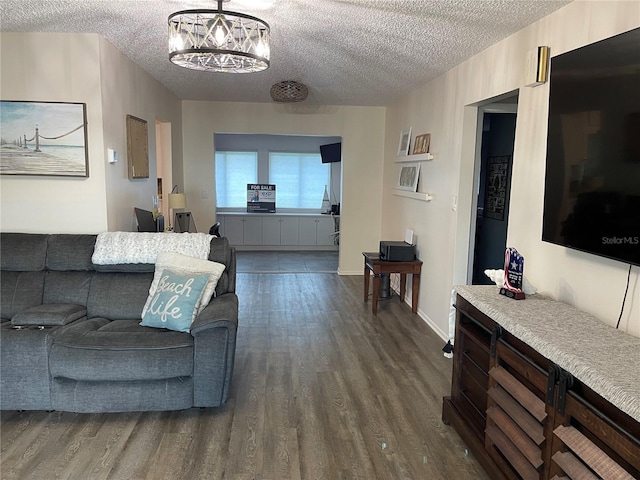 living room with an inviting chandelier, dark hardwood / wood-style floors, and a textured ceiling