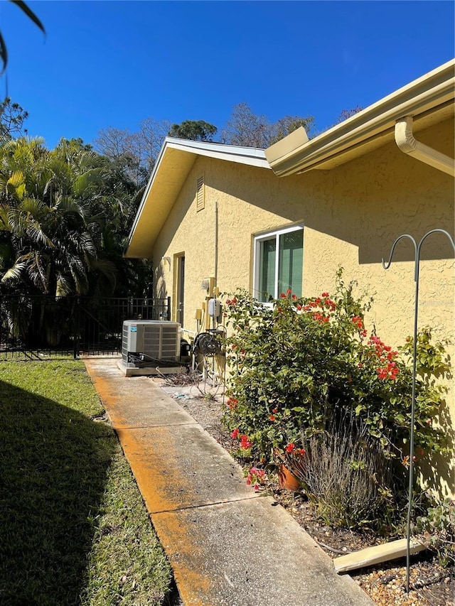 view of side of property with a lawn and central air condition unit