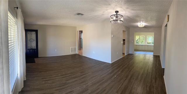 unfurnished room with dark hardwood / wood-style floors, a chandelier, and a textured ceiling