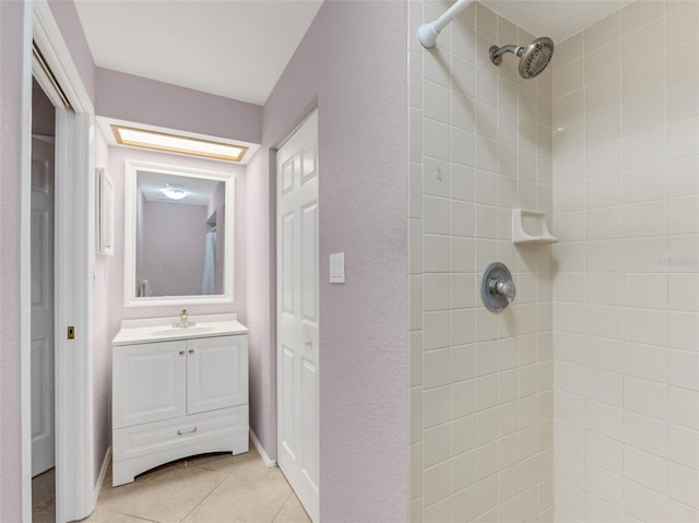 bathroom featuring a tile shower, vanity, and tile patterned flooring