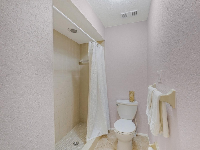 bathroom with a textured ceiling, tile patterned flooring, curtained shower, and toilet