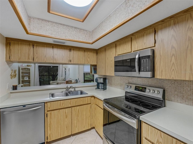 kitchen featuring appliances with stainless steel finishes, sink, light tile patterned floors, and decorative backsplash