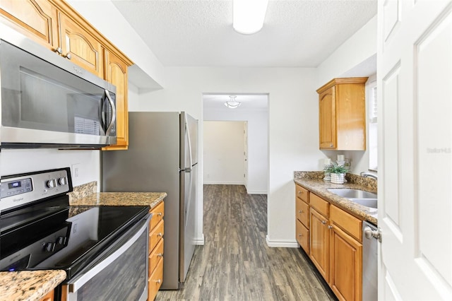 kitchen featuring sink, stainless steel appliances, light stone countertops, a textured ceiling, and dark hardwood / wood-style flooring