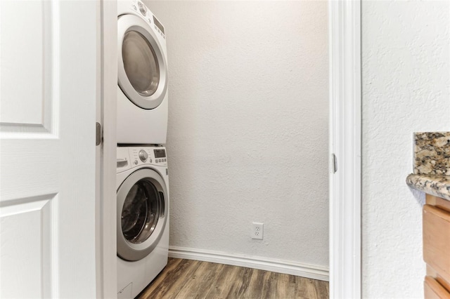 washroom featuring stacked washer / drying machine and dark hardwood / wood-style flooring