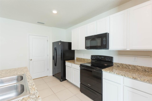 kitchen featuring sink, light tile patterned floors, light stone counters, white cabinets, and black appliances