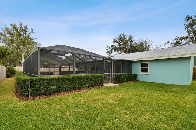 rear view of property with glass enclosure and a yard