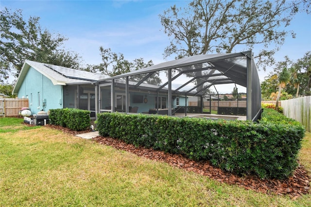 back of property with glass enclosure and a yard