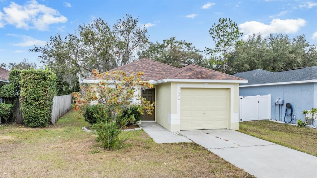 single story home with a garage and a front lawn